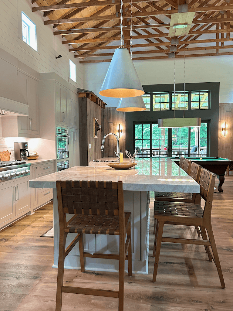 Looking across the kitchen counter to the porch and woods beyond — natural light, prep space, and a view from the cutting board