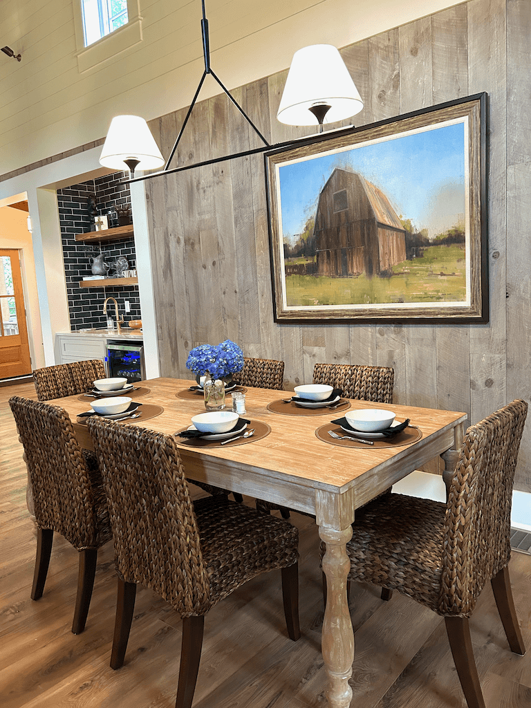 The dining table at The Barn — long wood farmhouse table beneath the timber trusses, seating eight comfortably