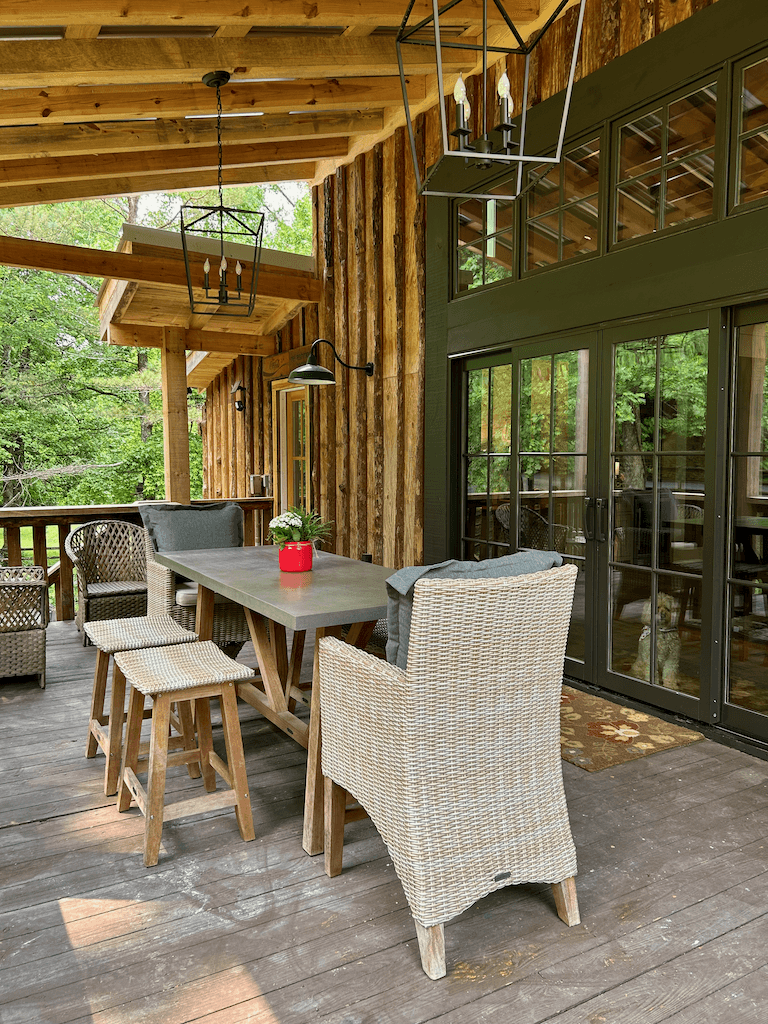 Outdoor dining on the back deck — covered porch with table and chairs, looking out over the trees